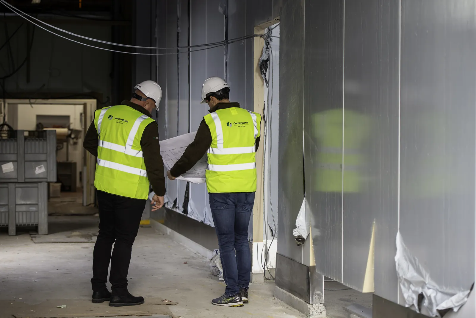 Reviewing drawings on site, hard hats and hi-vis on