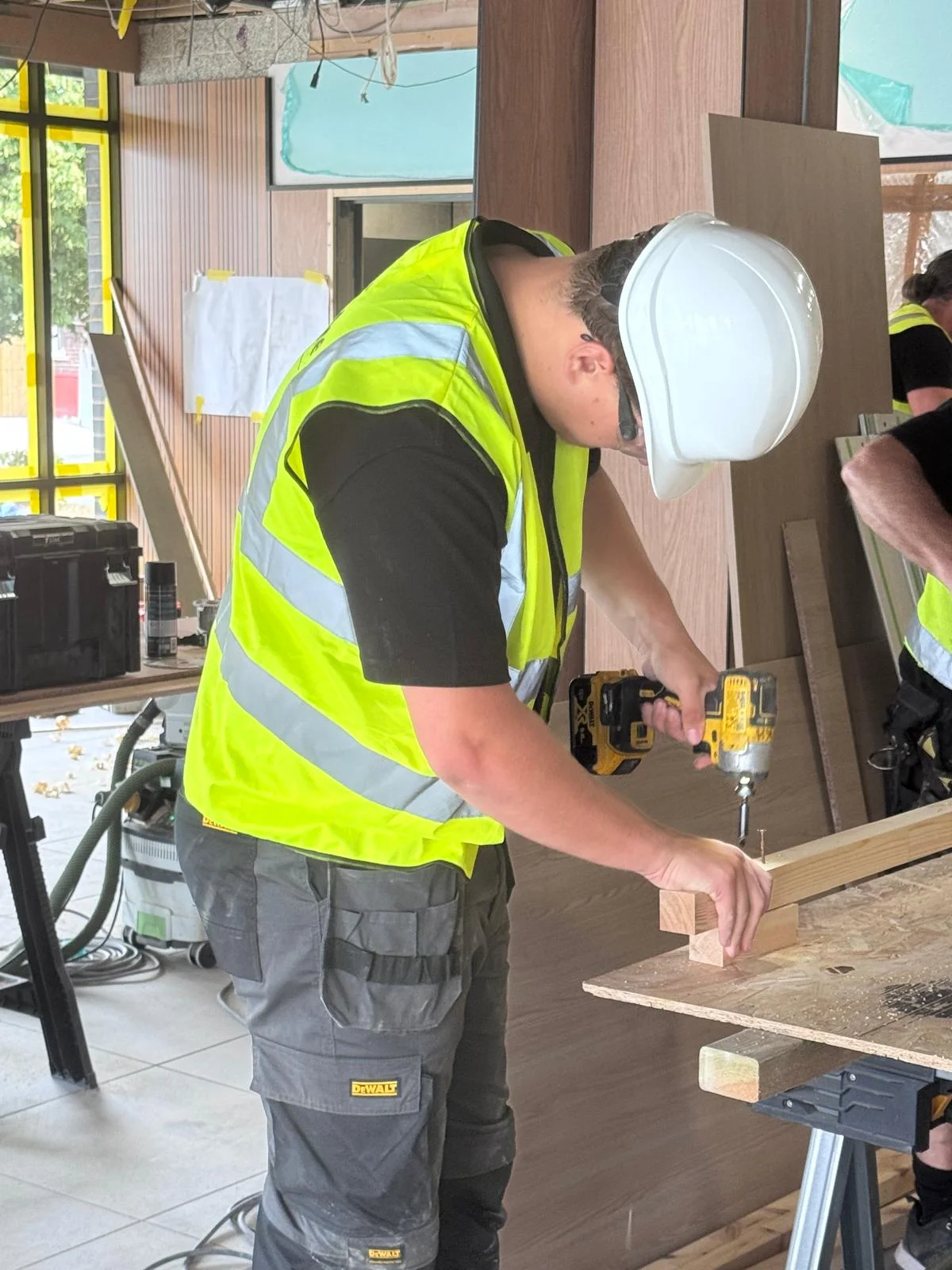 One of our apprentices fixing timber on site, in hard hat, safety glasses and hi-vis