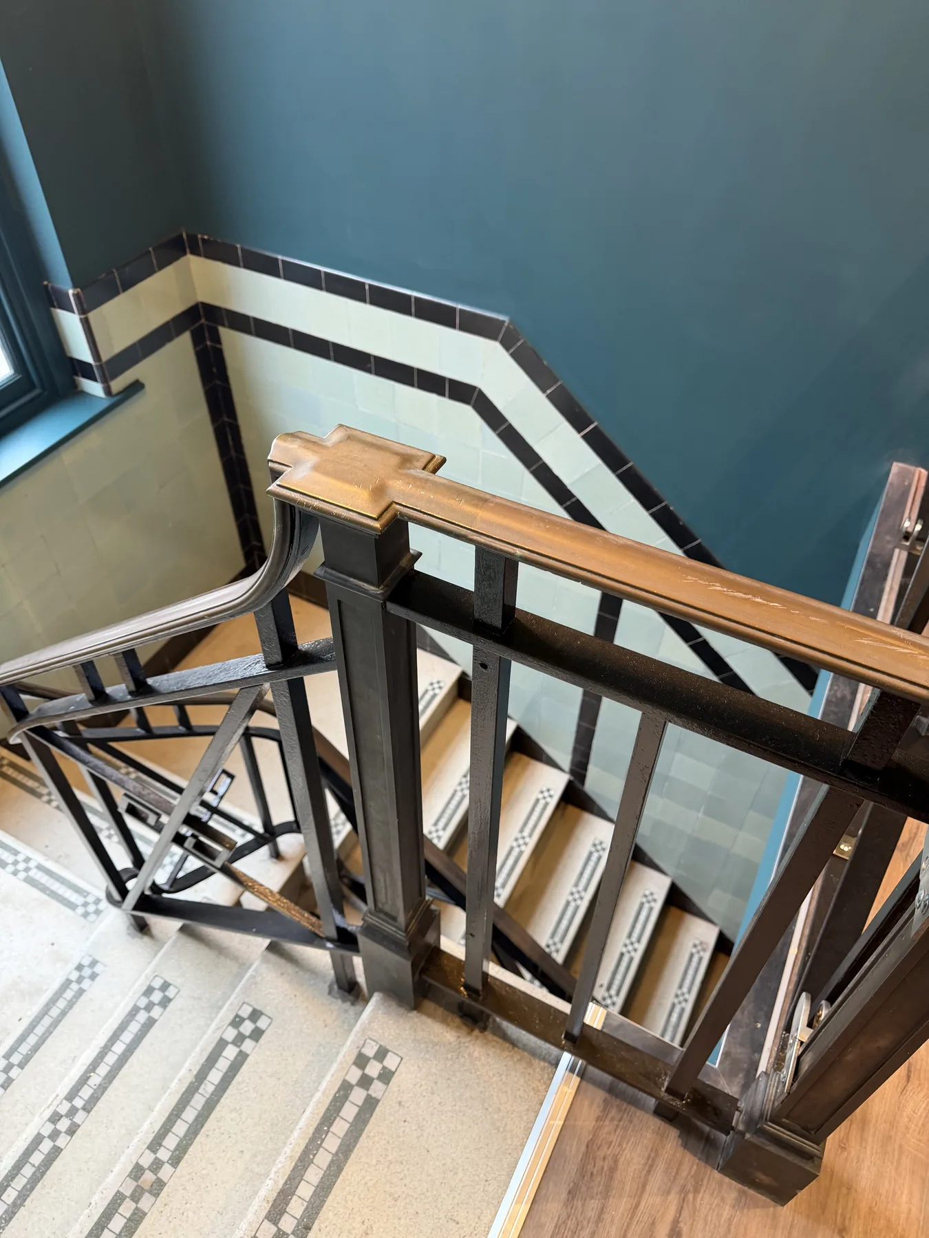 Heritage staircase with glazed wall tiles, terrazzo steps, timber handrail and iron balustrade