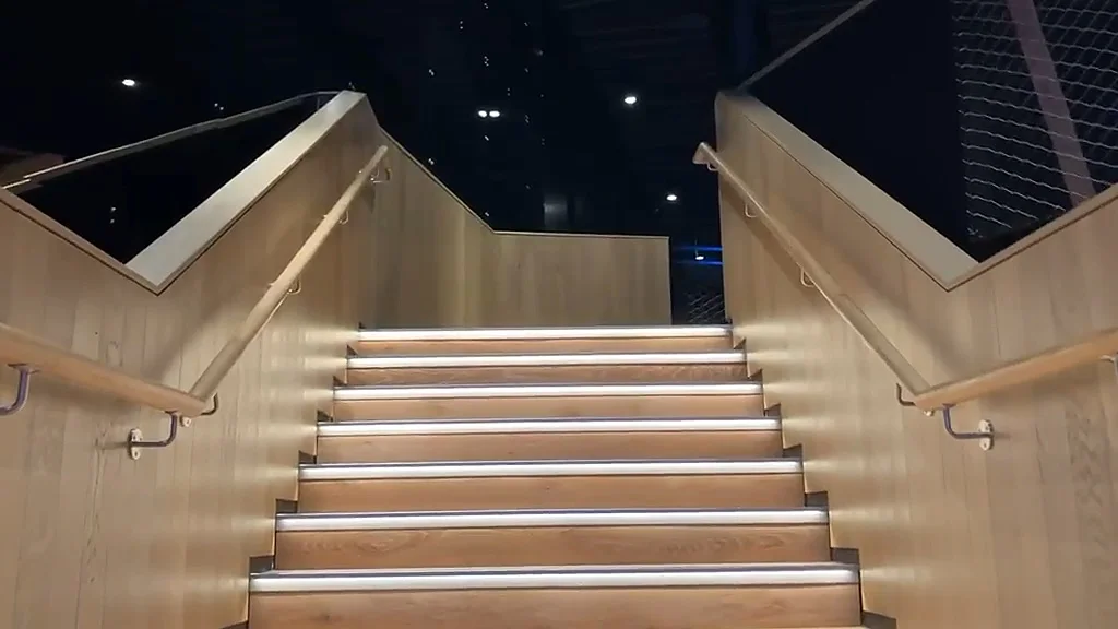 Oak staircase rising to a landing, with oak handrails on both sides