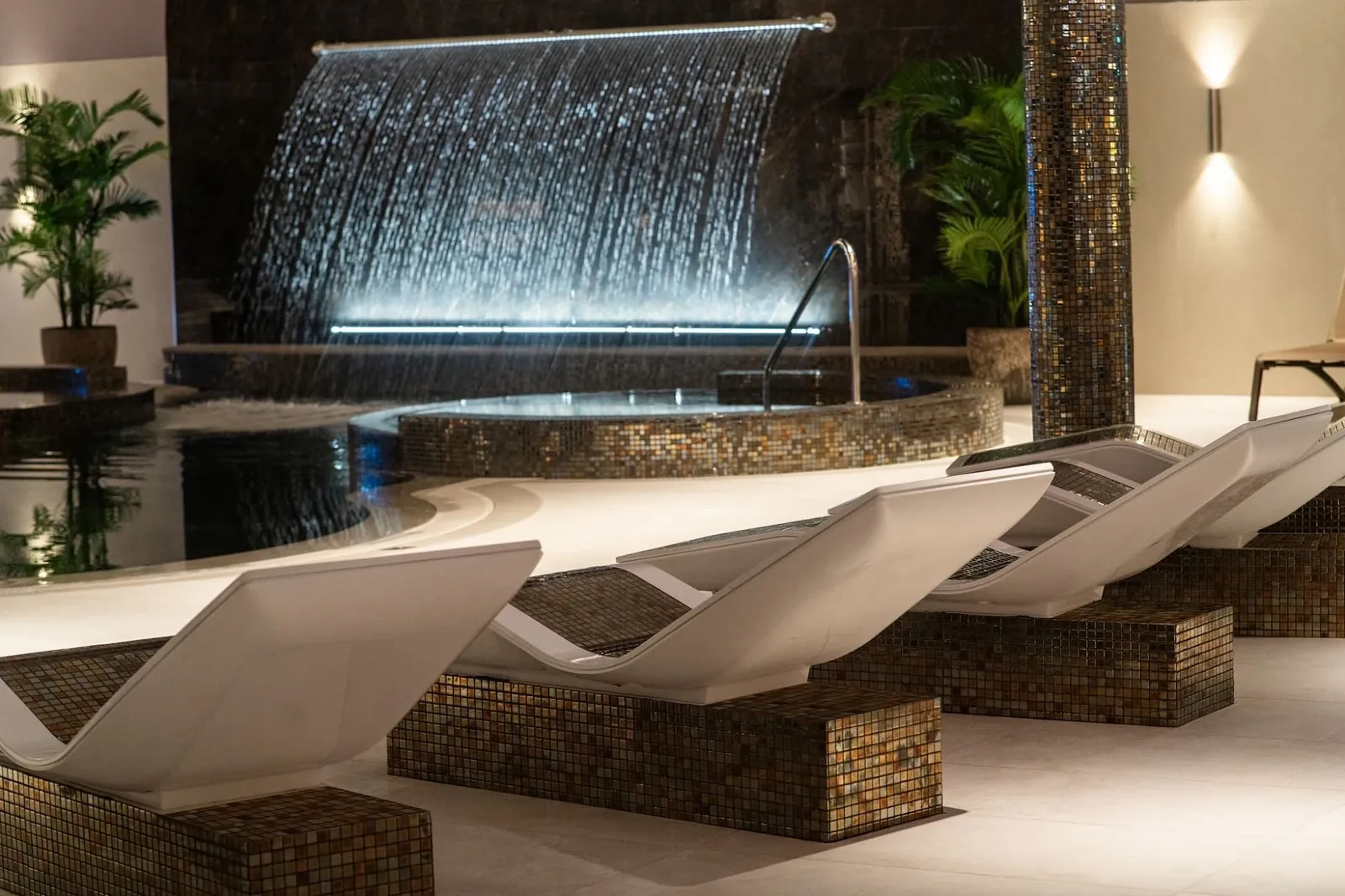 Heated mosaic loungers beside the pool at The Woodland Spa
