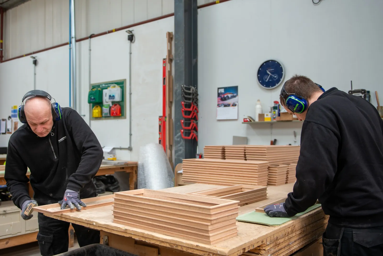 Joiners assembling timber frames, ear defenders and gloves on