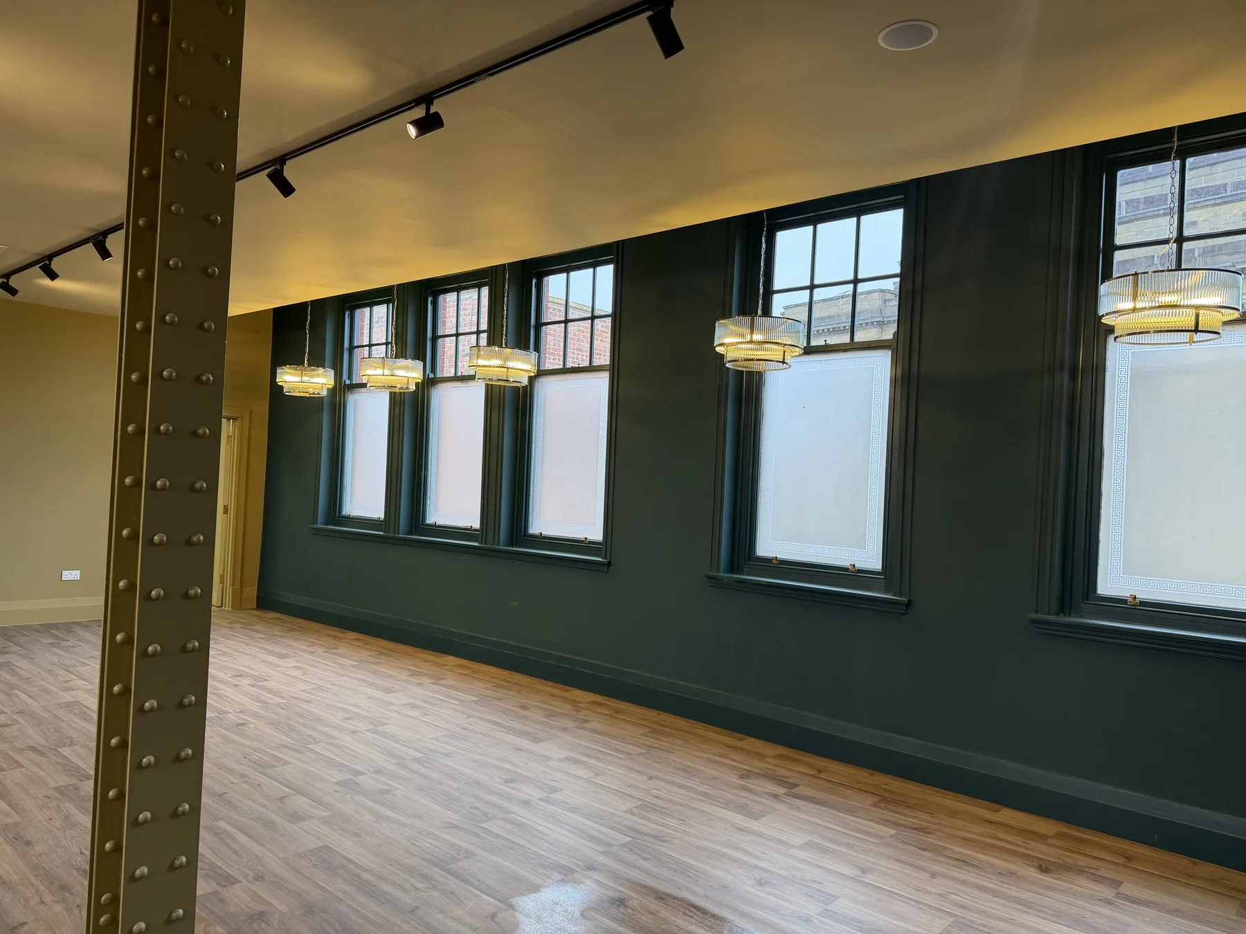 Dining room with tall sash windows, pendant lights and a riveted steel column