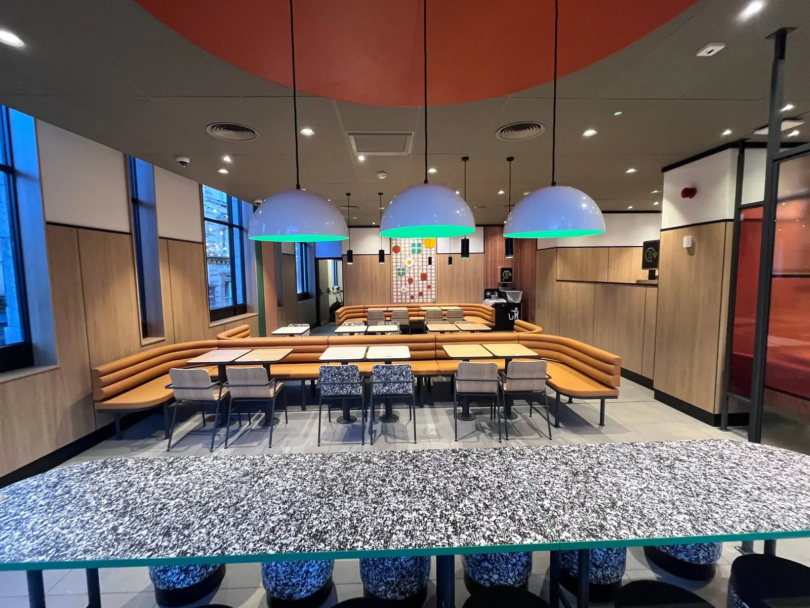 Communal table under feature pendants, banquette seating beyond